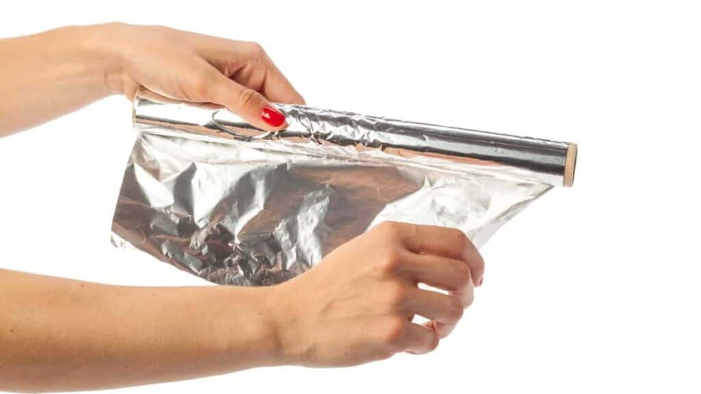 human hand holding a roll of foil on a white backg 2022 07 07 15 23 08 utc